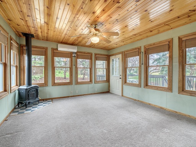 unfurnished sunroom with a wall unit AC, a wood stove, and a healthy amount of sunlight