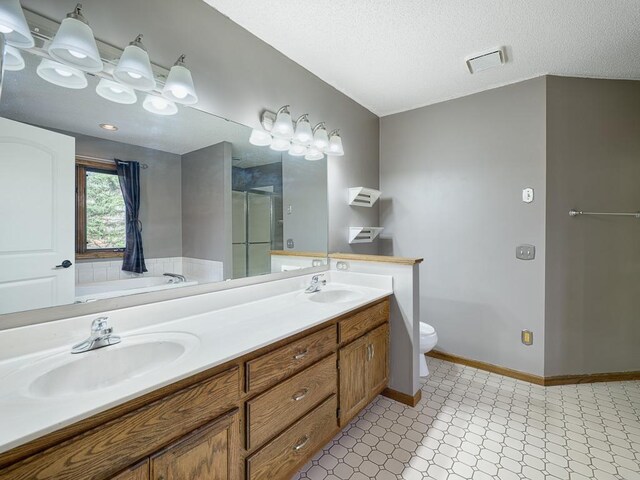 full bathroom with a shower stall, toilet, a sink, and double vanity