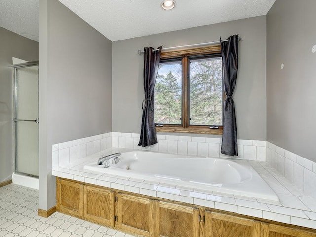full bathroom with a bath, baseboards, a textured ceiling, and a stall shower