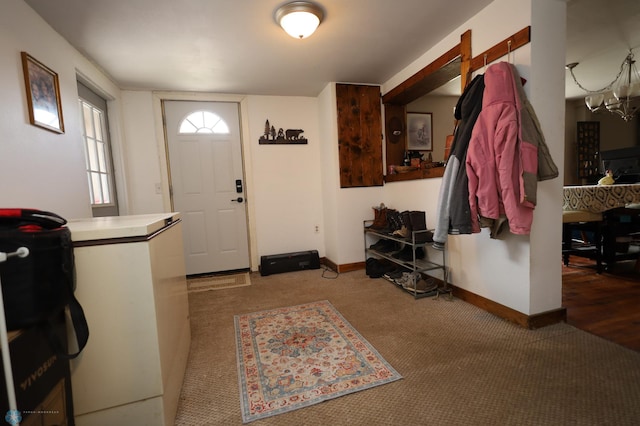 entryway with baseboards, carpet flooring, and a chandelier