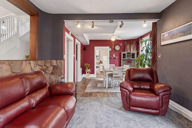 living area featuring baseboards, a ceiling fan, rail lighting, and wood finished floors