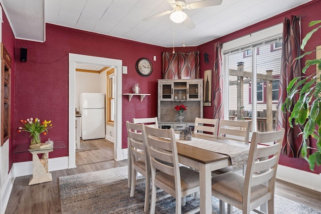 dining area featuring baseboards, crown molding, ceiling fan, and wood finished floors
