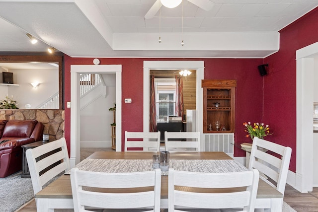 dining space with stairs, a ceiling fan, baseboards, and light wood-type flooring