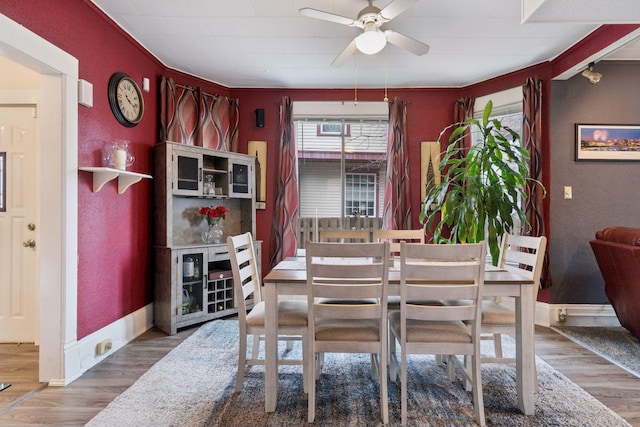 dining area with a ceiling fan, baseboards, and wood finished floors