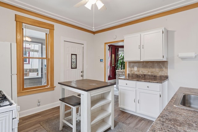 kitchen with white appliances, white cabinetry, a healthy amount of sunlight, and wood finished floors