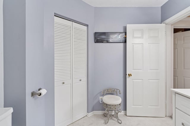 bathroom featuring vanity, baseboards, and a closet
