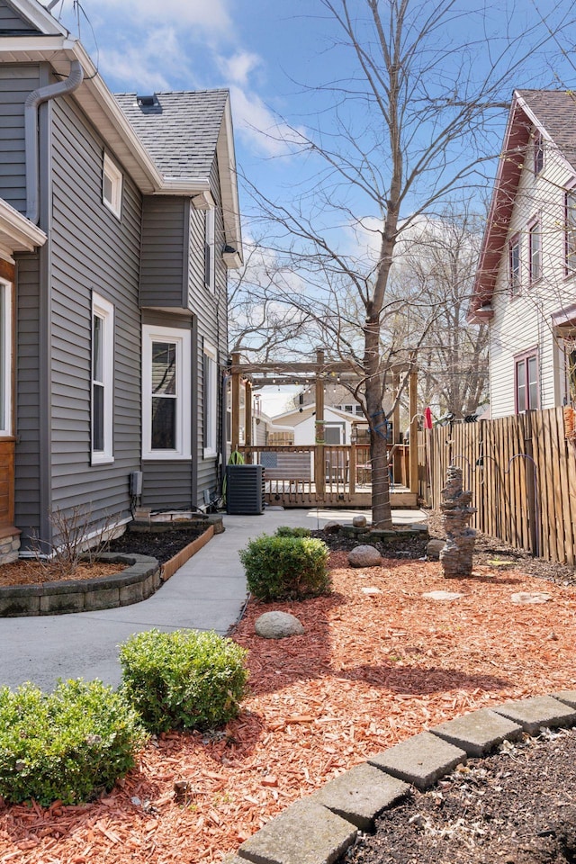 view of property exterior featuring fence, a shingled roof, central AC, and a patio area