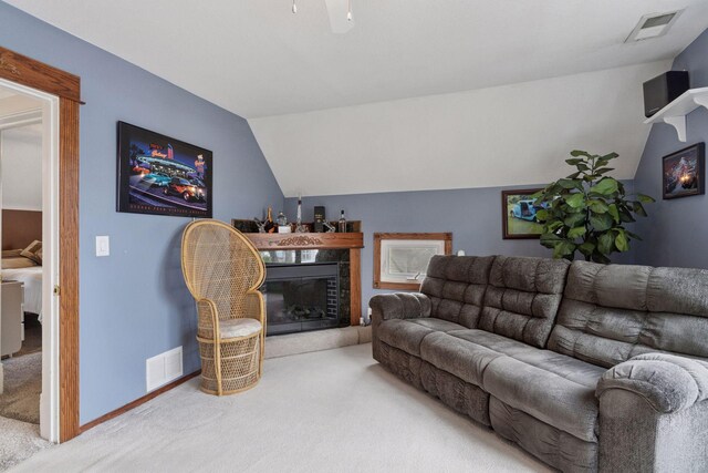 carpeted living room featuring baseboards, a fireplace with raised hearth, lofted ceiling, and visible vents
