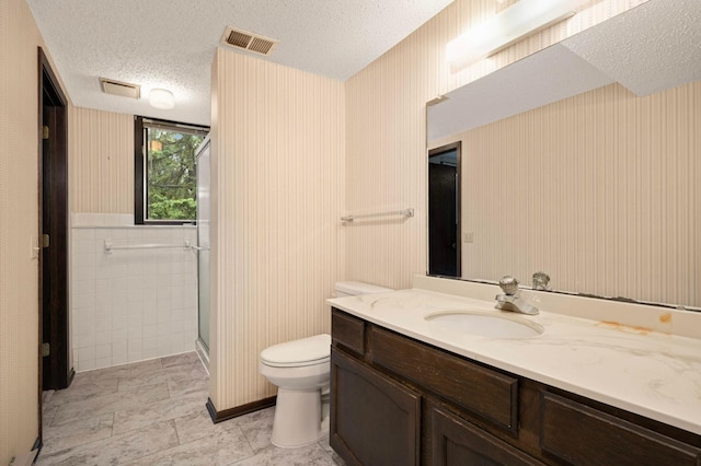 5410 Creek View Ln, Edina, MN 55439 - bathroom with a textured ceiling, toilet, vanity, a shower with door, and tile walls