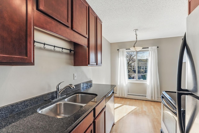 kitchen with stainless steel appliances, dark stone countertops, a sink, light wood-type flooring, and pendant lighting