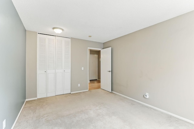 unfurnished bedroom featuring baseboards, a closet, and light colored carpet