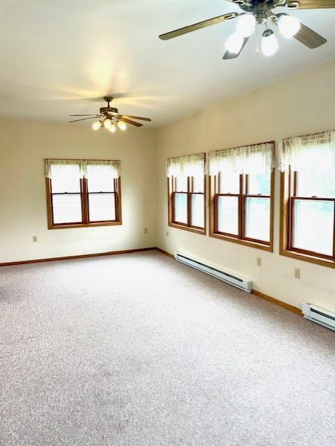 unfurnished room featuring carpet, baseboards, ceiling fan, and baseboard heating