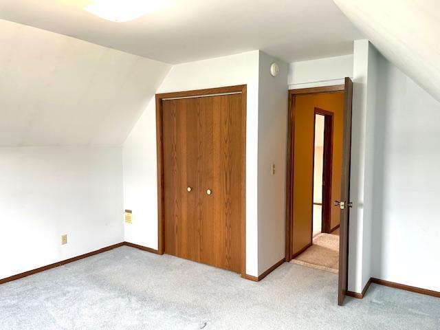 bonus room with baseboards, lofted ceiling, and light colored carpet