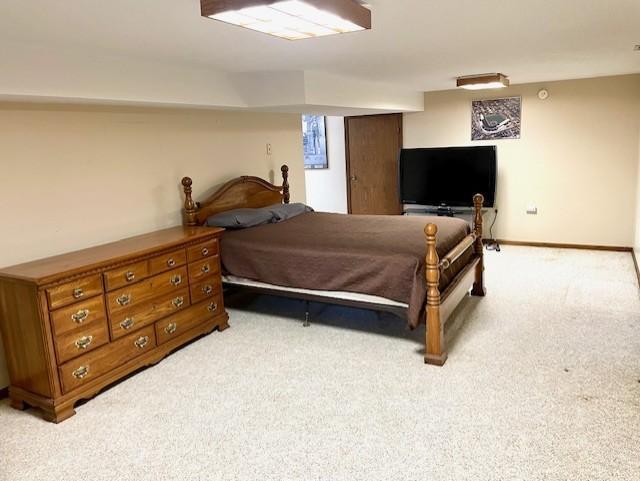 bedroom with light colored carpet and baseboards