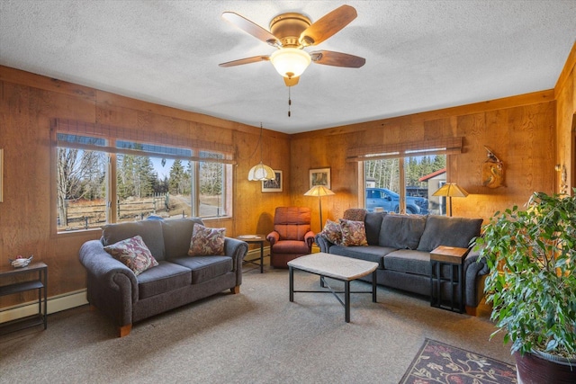 living room with wood walls, a ceiling fan, a textured ceiling, and carpet floors