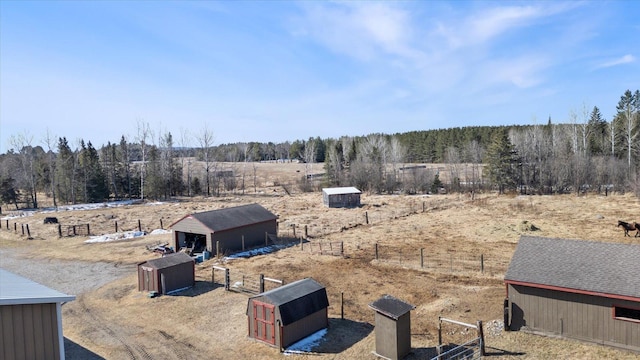 view of yard featuring a forest view, a pole building, a rural view, an outdoor structure, and fence