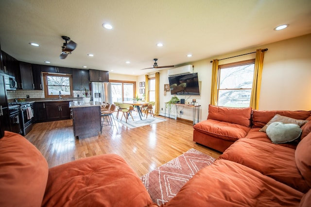 1474 Aldrich Ct, Faribault, MN 55021 - living area with a ceiling fan, baseboard heating, a wall unit AC, recessed lighting, and light wood-type flooring