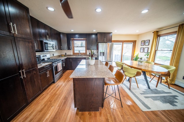 1474 Aldrich Ct, Faribault, MN 55021 - kitchen with a breakfast bar, light wood finished floors, a sink, a kitchen island, and appliances with stainless steel finishes
