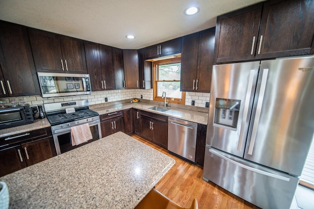 1474 Aldrich Ct, Faribault, MN 55021 - kitchen featuring a sink, tasteful backsplash, light wood-type flooring, dark brown cabinets, and appliances with stainless steel finishes