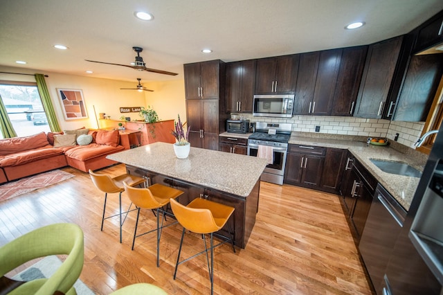 1474 Aldrich Ct, Faribault, MN 55021 - kitchen featuring a center island, a kitchen bar, backsplash, stainless steel appliances, and light wood-type flooring