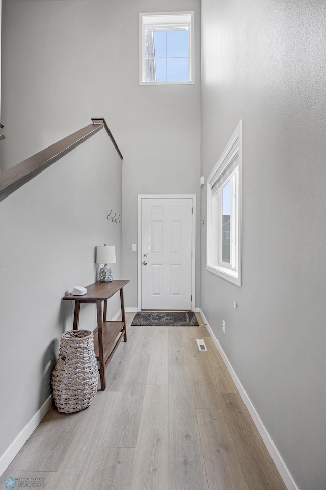foyer entrance with wood finished floors, visible vents, and baseboards