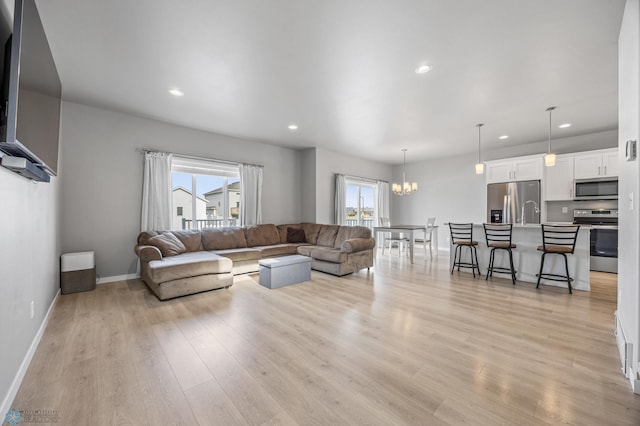 living room featuring light wood-type flooring, an inviting chandelier, and recessed lighting
