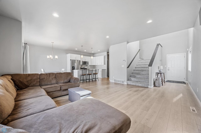 living room with recessed lighting, a notable chandelier, light wood-type flooring, stairs, and visible vents