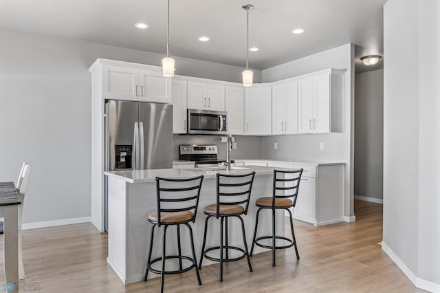kitchen with stainless steel appliances, light countertops, white cabinetry, light wood-type flooring, and a kitchen breakfast bar