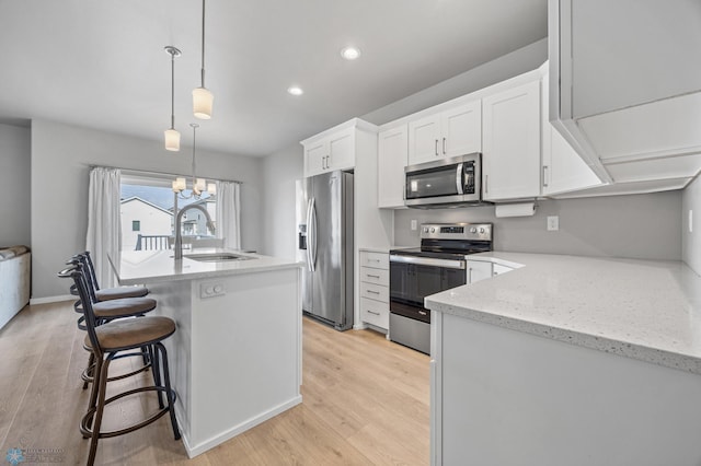 kitchen featuring white cabinetry, a sink, appliances with stainless steel finishes, recessed lighting, and light wood finished floors