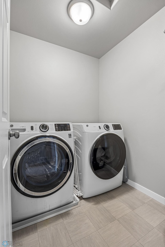 laundry area with tile patterned floors, washer and dryer, laundry area, and baseboards