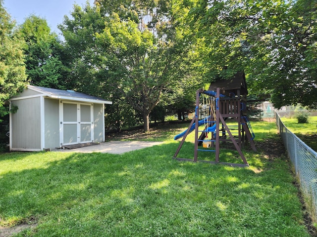 view of yard featuring a playground, a shed, an outbuilding, and fence