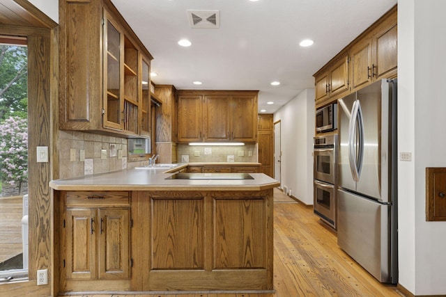 13982 Mount Ter, Minnetonka, MN 55345 - kitchen with stainless steel appliances, a sink, a peninsula, light wood-style flooring, and light countertops