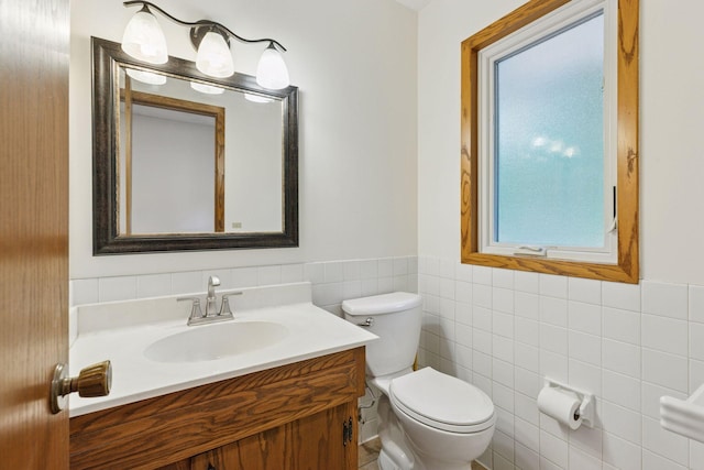 13982 Mount Ter, Minnetonka, MN 55345 - half bathroom featuring tile walls, toilet, vanity, and a wainscoted wall