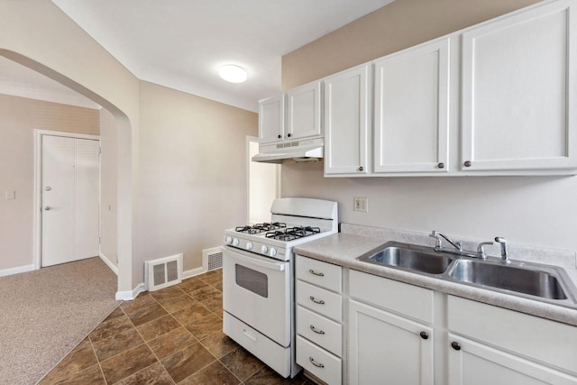 kitchen with white range with gas cooktop, under cabinet range hood, a sink, arched walkways, and white cabinets