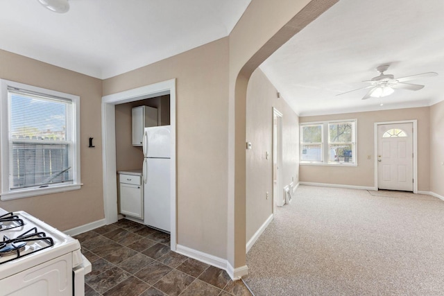 kitchen featuring white appliances, baseboards, arched walkways, and a ceiling fan