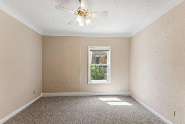 spare room featuring a textured wall, carpet floors, a textured ceiling, ceiling fan, and baseboards