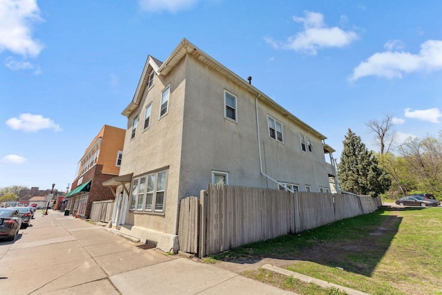 view of side of property featuring stucco siding and fence