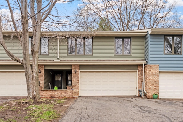 multi unit property with an attached garage, brick siding, and aphalt driveway