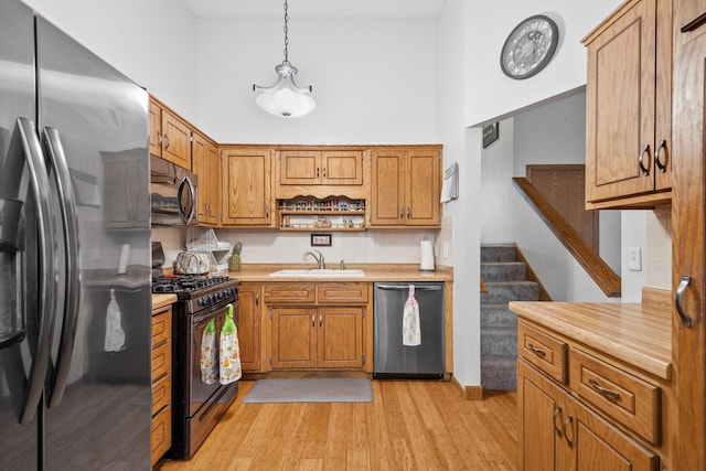 kitchen featuring light countertops, backsplash, a sink, light wood-type flooring, and appliances with stainless steel finishes