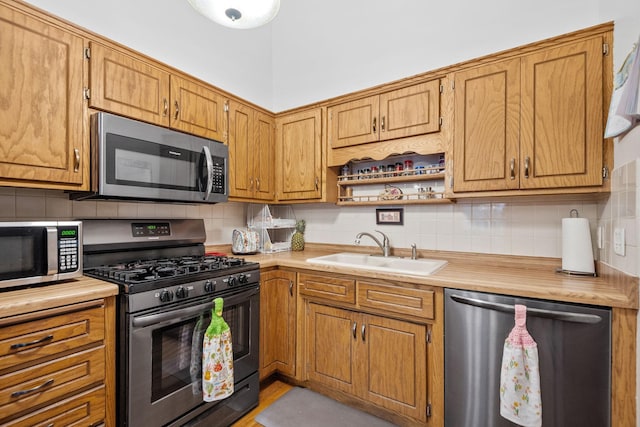 kitchen with brown cabinets, stainless steel appliances, open shelves, a sink, and tasteful backsplash