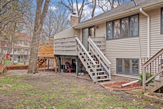 back of house featuring a chimney, roof with shingles, a deck, and stairs