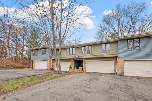 view of front of property with an attached garage, brick siding, and driveway
