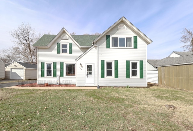 rear view of house featuring a lawn, an outbuilding, and a detached garage