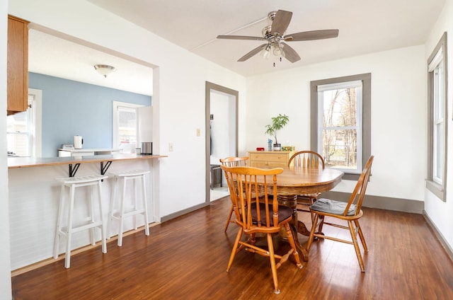 dining space with baseboards, a ceiling fan, and wood finished floors