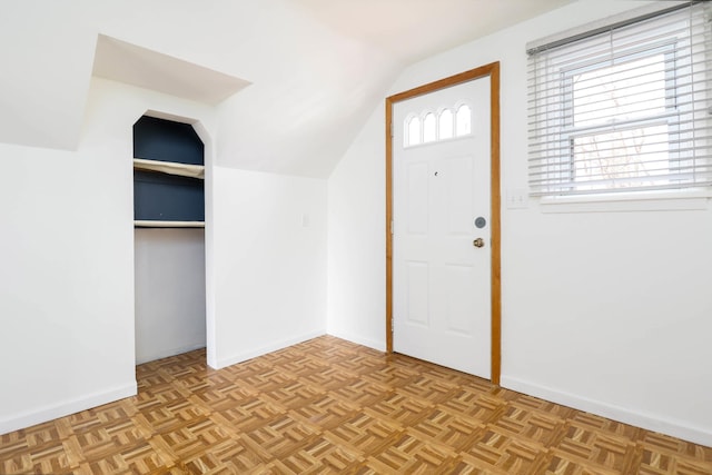 foyer featuring lofted ceiling and baseboards