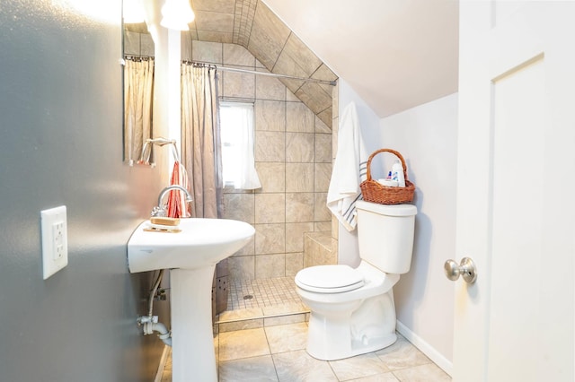 full bath with tile patterned floors, toilet, a tile shower, baseboards, and lofted ceiling