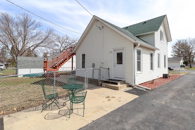 back of property featuring fence, a patio, and a shingled roof