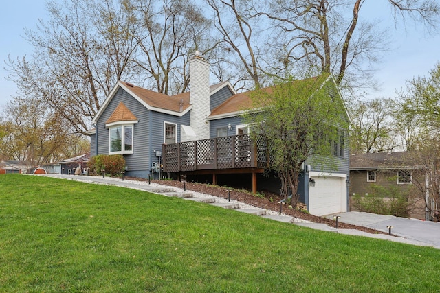 rear view of property with a garage, a deck, a chimney, a lawn, and driveway