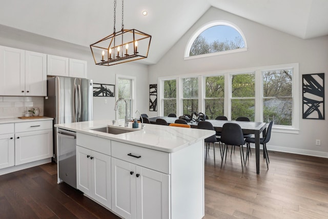 kitchen with dark wood-style flooring, a sink, high vaulted ceiling, an island with sink, and stainless steel appliances