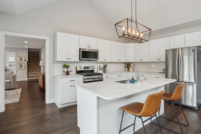 kitchen with a kitchen breakfast bar, high vaulted ceiling, white cabinetry, a sink, and appliances with stainless steel finishes